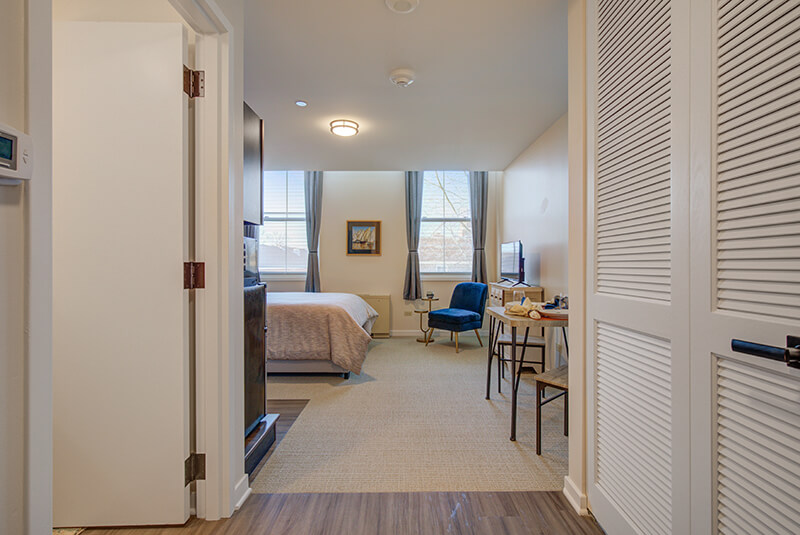 View from entryway into bedroom featuring large windows and workspace at Amazing Grace Senior Living