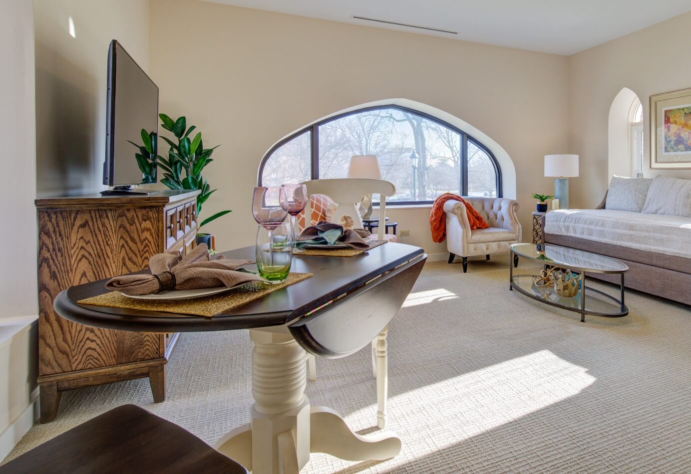 Bright senior living apartment interior with large window, modern furniture, and dining area at Amazing Grace Senior Living