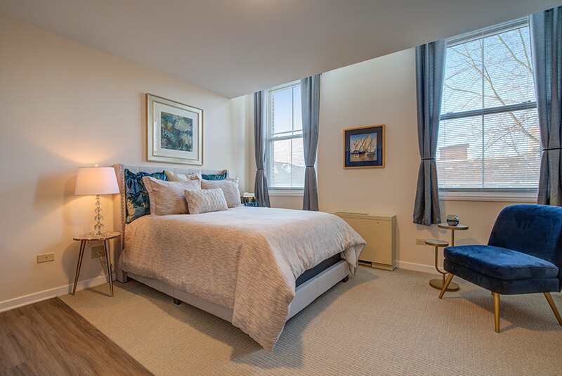 Elegant bedroom corner with large windows and cozy seating at Amazing Grace Senior Living