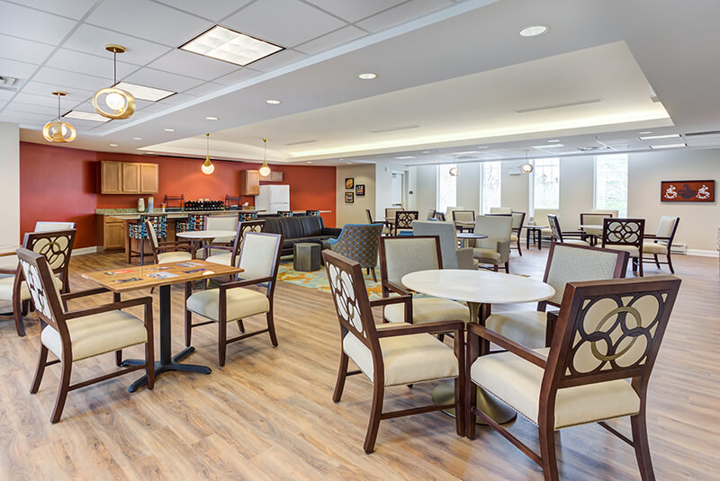 Modern bistro with café seating, pendant lights, and a refreshment counter at Amazing Grace Senior Living