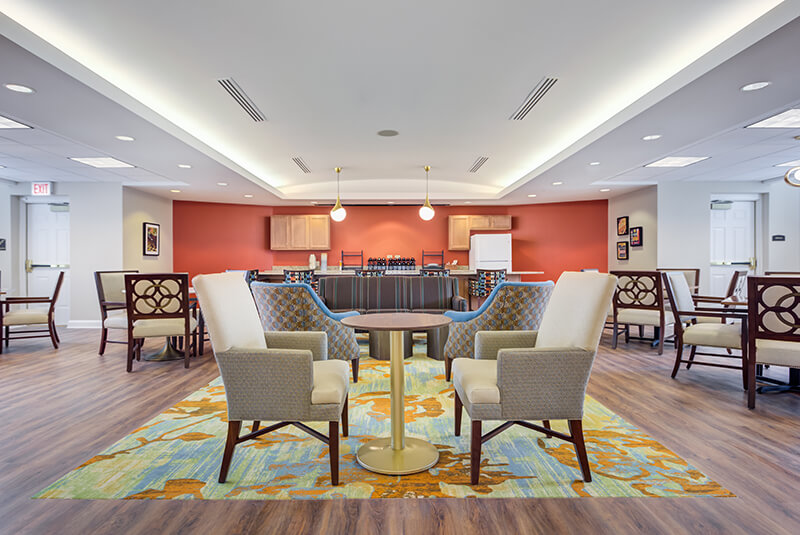 Comfortable bistro seating area with colorful accents and wood flooring at Amazing Grace Senior Living
