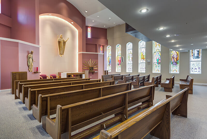 Chapel side angle showing seating and stained-glass artwork at Amazing Grace Senior Living