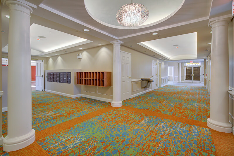 Bright first-floor corridor with mailboxes, columns, and decorative lighting at Amazing Grace Senior Living