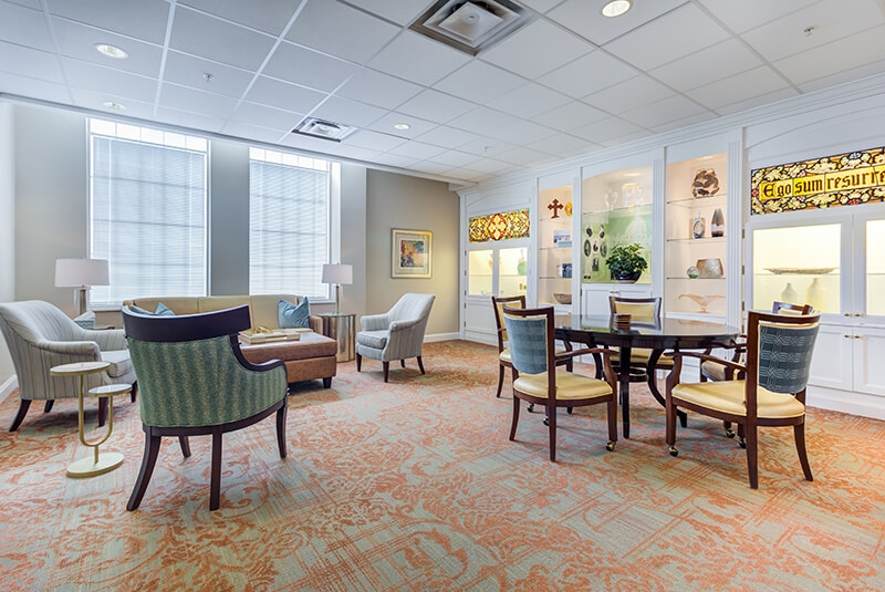 Discovery room with elegant display shelving, stained glass, and comfortable seating at Amazing Grace Senior Living