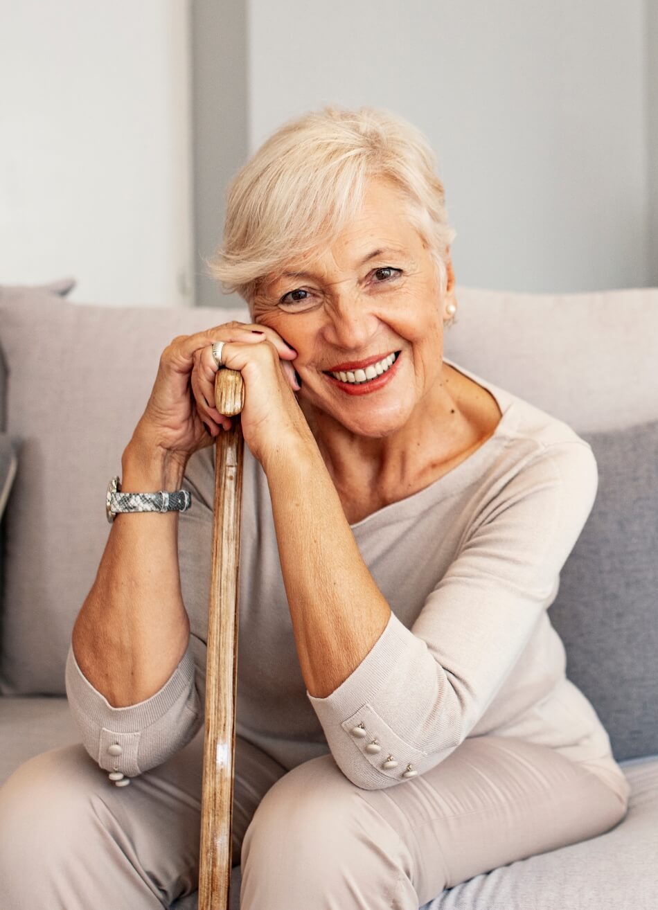 Portrait of a happy senior woman sitting on a couch and smiling confidently at Amazing Grace Senior Living
