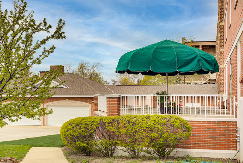 Outdoor patio area with green canopy and landscaped surroundings at Amazing Grace Senior Living