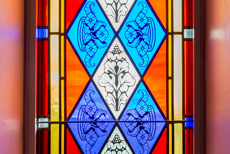 Vibrant stained-glass panel featuring geometric floral design in red, blue, and orange at Amazing Grace Senior Living