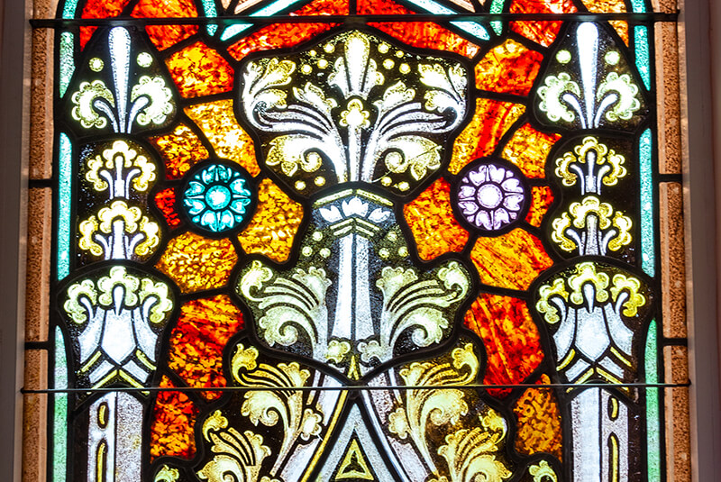 Ornate stained-glass window with rich red and gold tones at Amazing Grace Senior Living