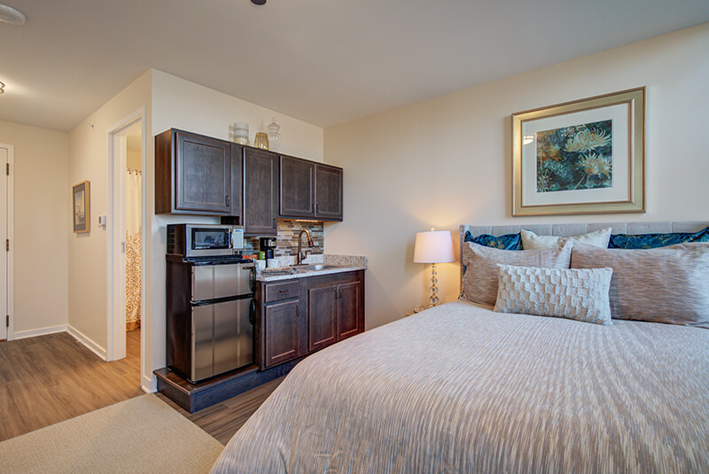 Studio bedroom with kitchenette and queen bed at Amazing Grace Senior Living