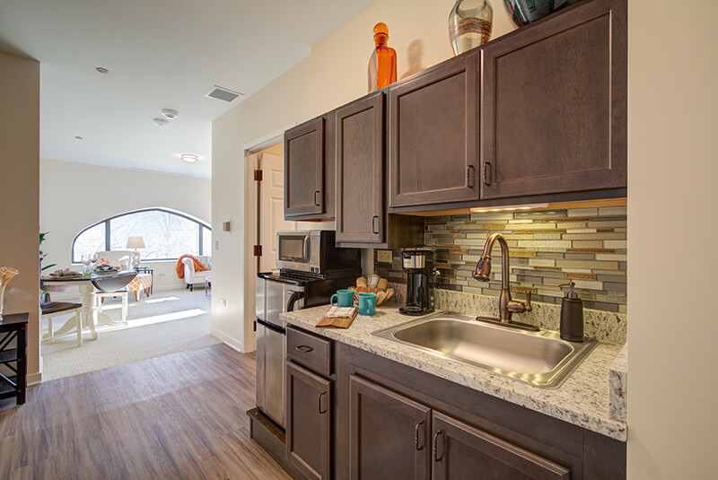 Modern senior living studio apartment with open layout, kitchenette, and dining space at Amazing Grace Senior Living