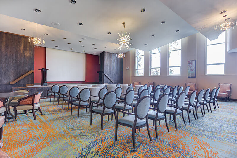 Spacious theater room with presentation stage and seating area for community gatherings at Amazing Grace Senior Living