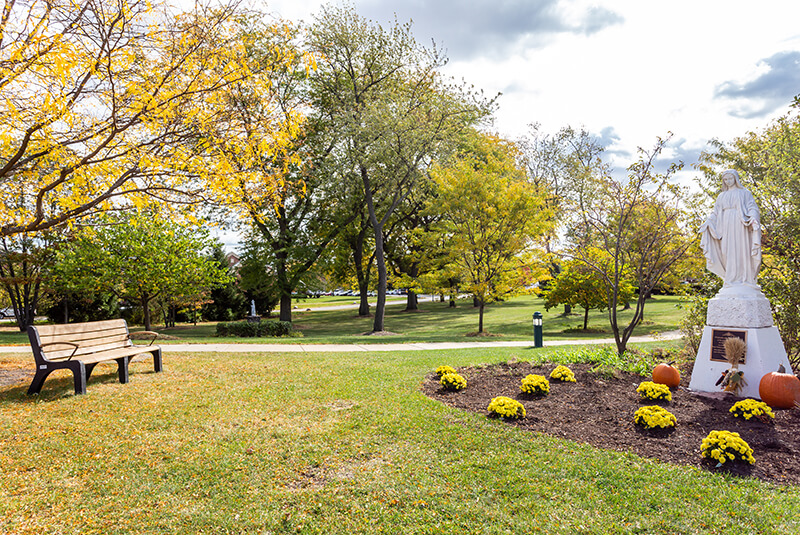 Park-like outdoor space with statue and benches at Amazing Grace Senior Living